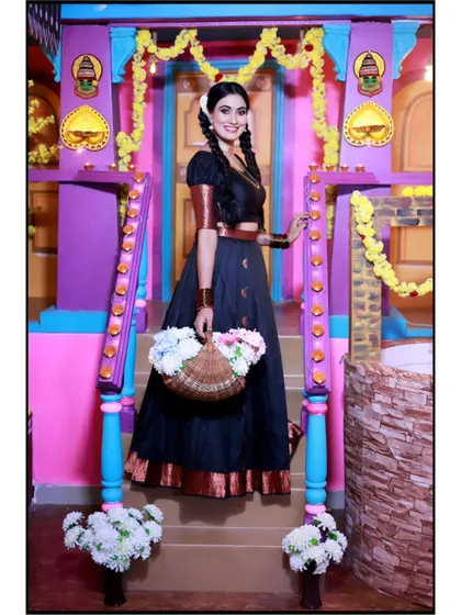 A full-length shot of the traditional black half-saree, captured in a colorful and festive studio setting.