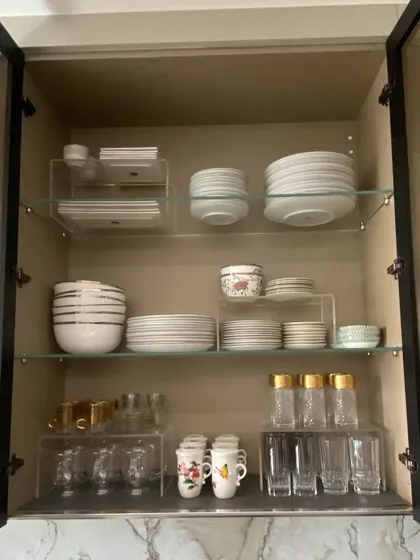 We used acrylic risers in this cabinet to create separate zones for different types of plates, bowls, and glasses, making the most of the available shelf height.