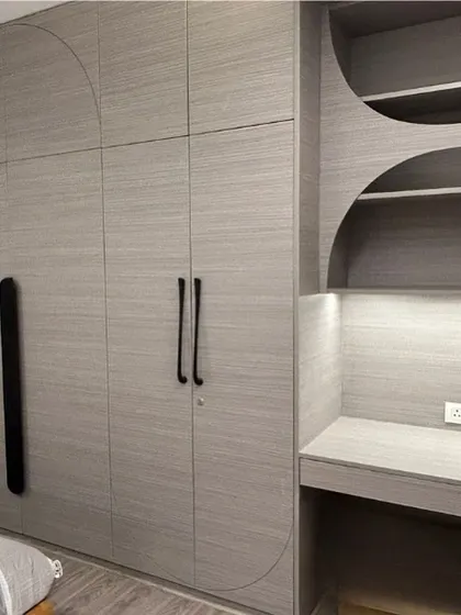 This monochrome unit combines a wardrobe and a study desk. The curved geometric patterns routed into the laminate add a subtle design detail, unifying the two functional zones into one cohesive piece of furniture.