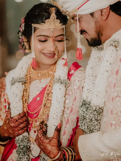 A tender moment as the groom gently holds his bride, their traditional headwear and garlands adding to the beauty of the scene.