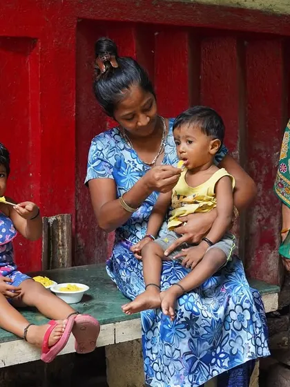 A mother feeds her young children, a touching moment from our food service initiative. Every meal is a plate of love and hope.