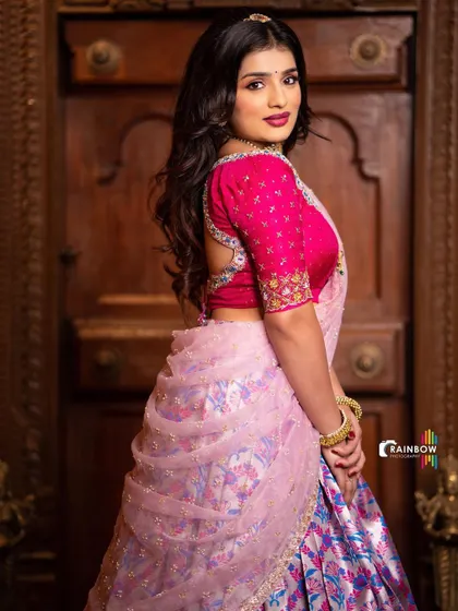 A side profile showing the elegant drape of the sheer pink dupatta over the patterned skirt.