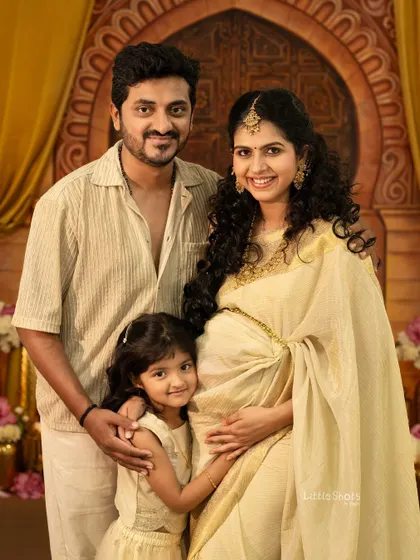 A beautiful, traditional family portrait celebrating a new arrival. The mother's pregnancy glow, the father's pride, and the big sister's excitement are all captured in this stunning photo.