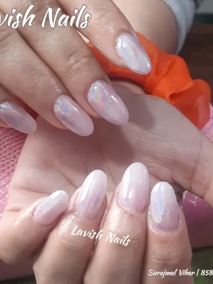 A beautiful set of almond-shaped nails with a sheer, iridescent finish that catches the light with hints of pink and blue.