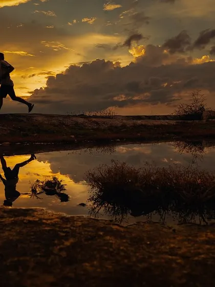 A breathtaking reflection of a couple against a dramatic sunset sky. This is a perfect example of how we use natural elements to create artistic and memorable photographs.