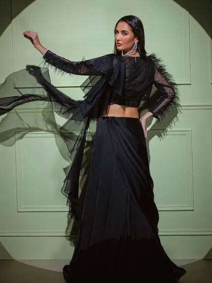 The black feather-sleeve saree in motion, showcasing the dramatic flair of the sleeves and the flowing drape.