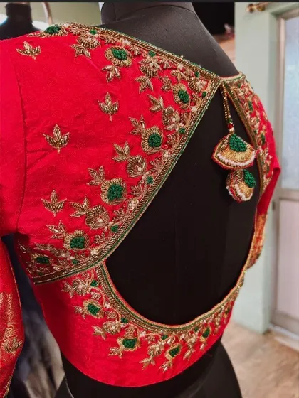 A close-up of the red cutout blouse, highlighting the neat embroidery work and the custom-made tassels that perfectly match the design.