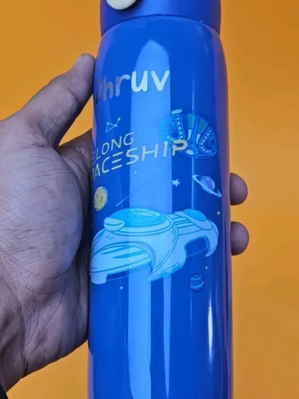 A close-up of the spaceship-themed bottle, showing the detail in the design and the custom name 'Dhruv'. These bottles are both stylish and practical for everyday use.