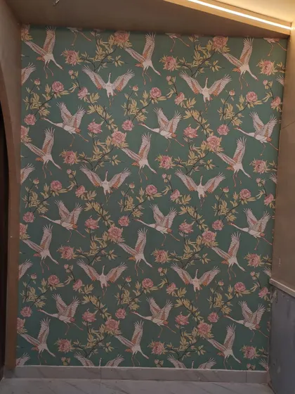 A green wallpaper with a pattern of flying cranes and flowers.