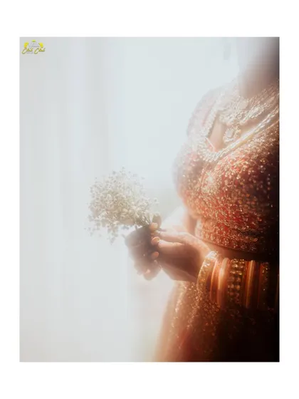 An artistic and dreamy bridal portrait. The soft, hazy light and the focus on the delicate flowers she holds create a romantic and ethereal mood.