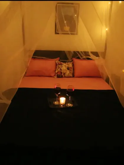 A straight-on view of the cabana bed setup, showing the cozy pink and black bedding and the intimate lighting.