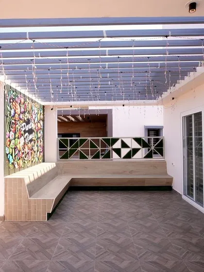 A wide view of the party terrace, showing the expansive space, built-in seating, and modern pergola. The design offers a fantastic view and plenty of room for entertaining guests.