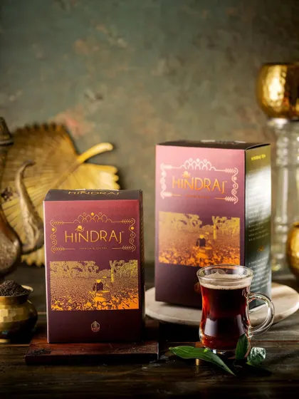 A dark and moody still life of Hindraj black tea. The rich, warm lighting and antique brass props create a sense of heritage and premium quality.