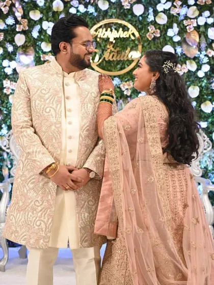 A sweet moment between the couple at their reception. Her pastel pink lehenga is paired with a natural, dewy makeup look and a simple wavy hairstyle.