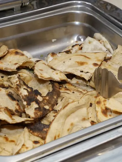 A tray of butter naan or roti, cut into pieces for easy serving at a buffet.