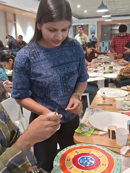 I provide individual guidance to ensure everyone is on the right track. Here, a participant is focused on painting her design, adding vibrant color to her mud and mirror art piece.