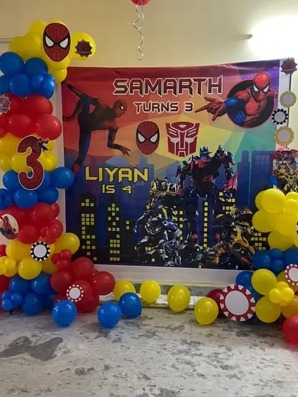 For a joint birthday party, I combined the Spiderman and Transformers themes. This setup features a custom banner for both kids and balloon columns in the classic red, blue, and yellow superhero colors.