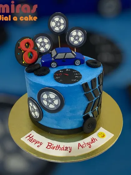 A cake for a car enthusiast, this design is all about wheels and speed. The blue cake is decorated with tires, a speedometer, and a car topper for an 8th birthday.