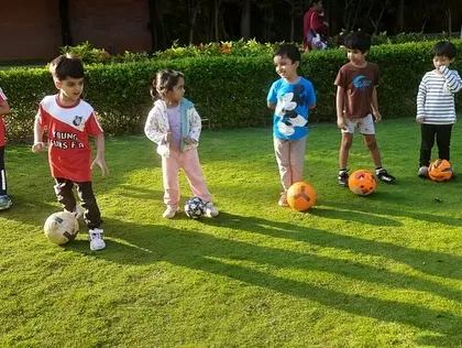 A group of young footballers, each with their own ball, ready for the next instruction. This shows our commitment to individual skill development within a group setting.