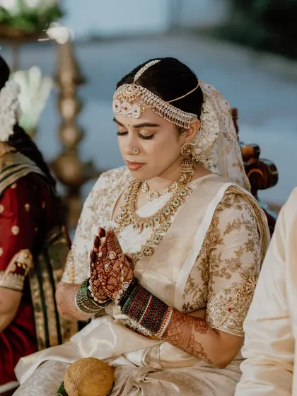 Pooja in a moment of prayer. The makeup is soft and reverent, perfect for the sanctity of the wedding rituals.