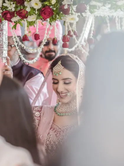 A beautiful, soft-focus shot of the bride's entrance under the phoolon ki chadar. Her happy, downward glance captures a moment of shy excitement.