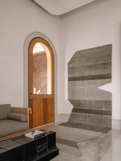 A view of the home office seating area, showing how the rug extends up the wall to become a piece of textile art. The arched doorway and custom furniture create a space that is both functional and inspiring.