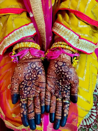 The bride's hands, rich with fresh henna and adorned with jewelry, ready for her Haldi or Mehendi ceremony.