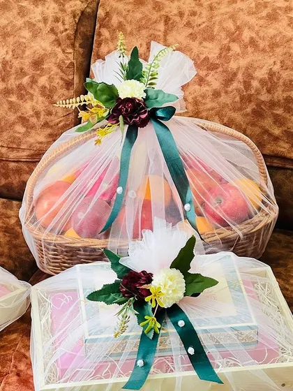 A full set of trousseau gifts, including a fruit basket and multiple boxes. The consistent floral toppers and ribbons create a unified and impressive display.
