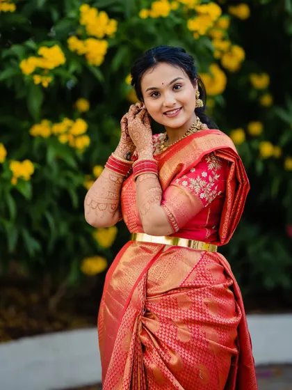 Devika adjusting her earring, a classic getting-ready shot that highlights her intricate jewelry.