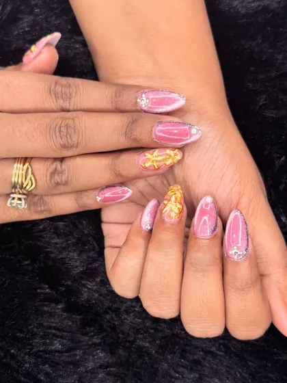 This design is all about pink and gold glamour. It combines a shimmering pink base with textured gold leaf accents and sparkling rhinestones at the cuticle.