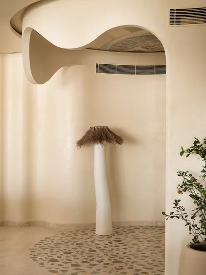 A detail of the sculptural floor lamp and the curved, textured walls of the coffee corner.