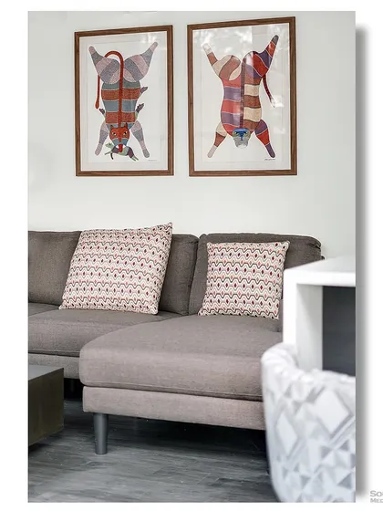 A detail shot of a modern living room inside a container home. The quirky, colorful art depicting stylized tigers adds a playful and artistic touch to the contemporary space.
