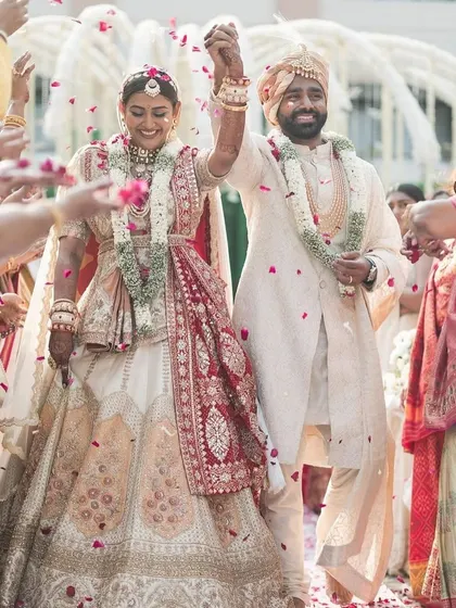 The walk of a lifetime. The happy couple makes their way through a shower of petals, surrounded by friends and family, after a beautiful ceremony in an elegant, all-white themed wedding.