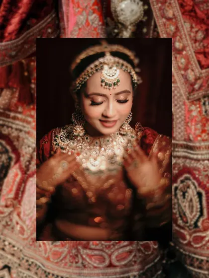 A close-up bridal portrait framed by the rich texture of her lehenga, highlighting her beautiful makeup and jewelry.