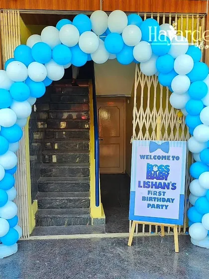 A welcoming balloon arch in blue and white for a Boss Baby first birthday party, complete with a custom welcome sign.
