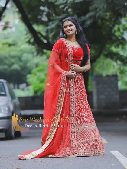 An outdoor shot of the red and gold lehenga, showing how its vibrant color stands out against a natural background.
