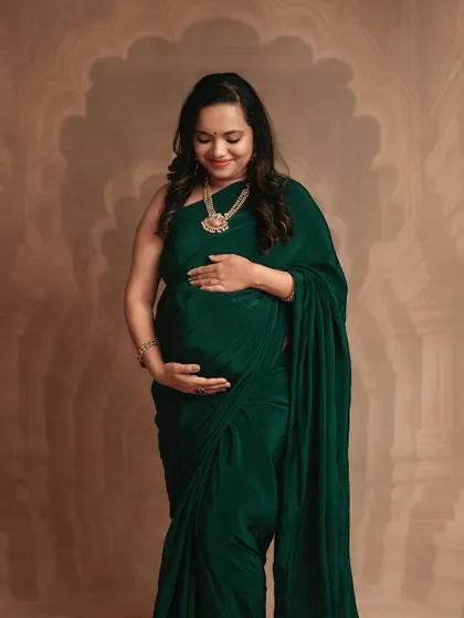 A classic solo portrait of a mom-to-be in a green saree. Her gentle smile and the way she holds her bump make this a truly heartwarming photo.