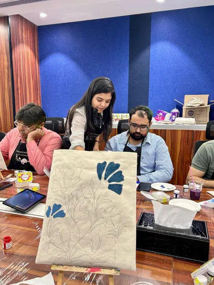 I love helping participants bring their ideas to life. Here, I'm assisting with the initial sketch on a tote bag before the painting begins.