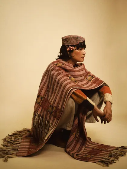 A profile shot that captures a quiet, contemplative mood. The way the shawl drapes creates beautiful lines, emphasizing the craftsmanship of the woven textile.