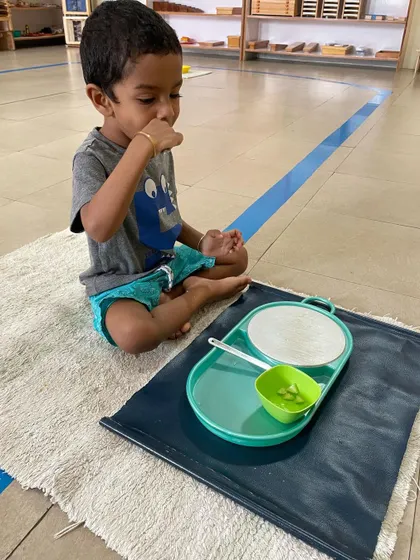 After completing a food preparation activity, this child sits down to enjoy the snack he prepared himself. This completes the work cycle, providing a sense of accomplishment and connecting his effort to a tangible result.