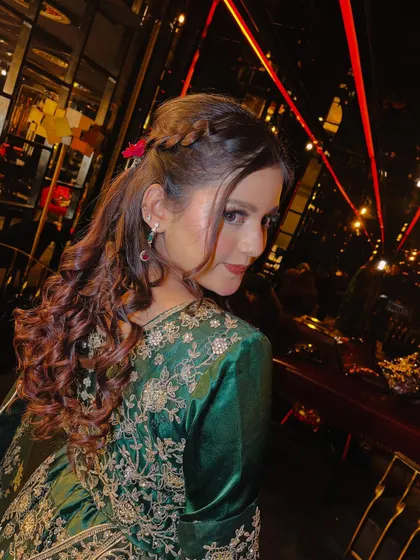 A lovely over-the-shoulder pose that highlights both the makeup and the beautiful hairstyle. The soft lighting enhances the model's glowing skin and the rich color of her outfit.
