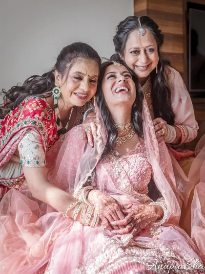 A moment of shared laughter between the bride, her mother, and her mother-in-law. A candid shot full of genuine happiness.