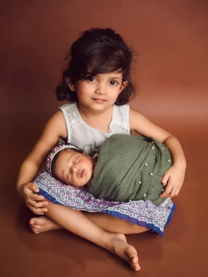 A beautiful portrait of two sisters. The older sister's protective and loving gaze is perfectly captured in this studio newborn session.