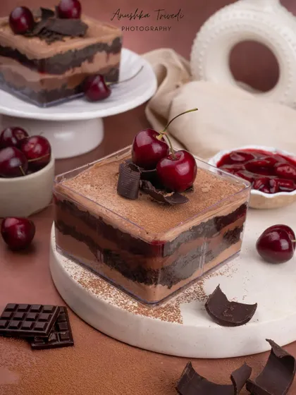 A layered black forest tub cake, looking decadent and rich with fresh cherry toppings.