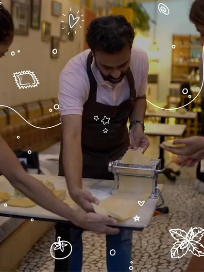 Using a traditional pasta machine to sheet the dough is a key step in our workshops. Here, I'm guiding a participant as they create the perfect thickness for their handmade ravioli.