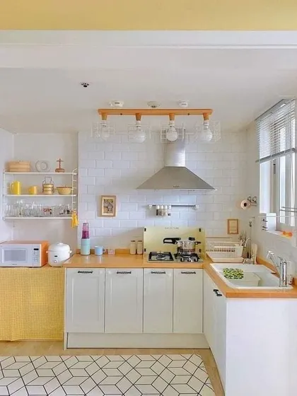 This cozy kitchen has a warm, slightly rustic feel with its wooden countertops and white shaker cabinets. The open shelving and geometric floor tiles add a touch of modern farmhouse charm.