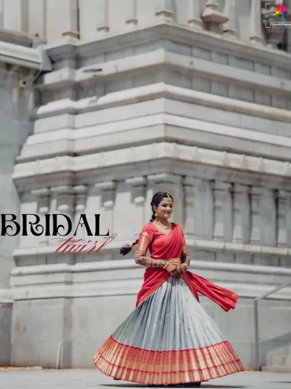 "Bridal Twist." A fun and dynamic shot of the bride twirling in her traditional half saree against a grand temple backdrop. It captures her joyful spirit and the beauty of her outfit.