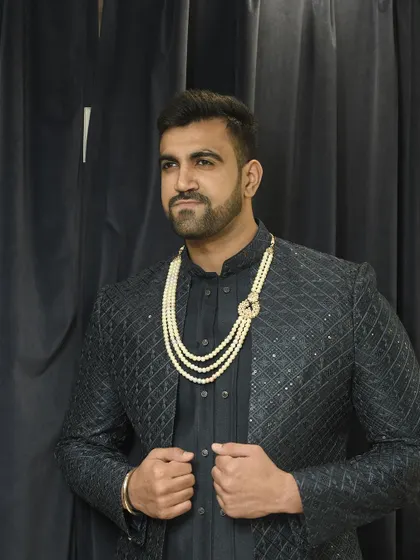 The client adjusts his jacket, giving a dynamic feel to this stylish, dark-toned ethnic look.