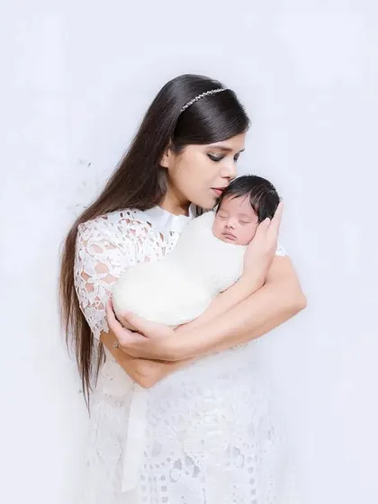 A mother gently kisses the forehead of her sleeping newborn. A simple, powerful image of maternal love, captured in a clean and bright style.