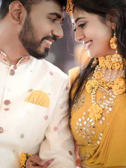 A close-up, intimate portrait of a couple during their Haldi ceremony. Their loving gaze and the beautiful yellow floral jewelry create a warm and romantic feel.